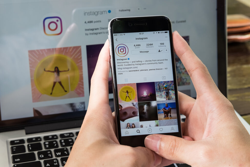 Person holding a phone and looking at social media on screen