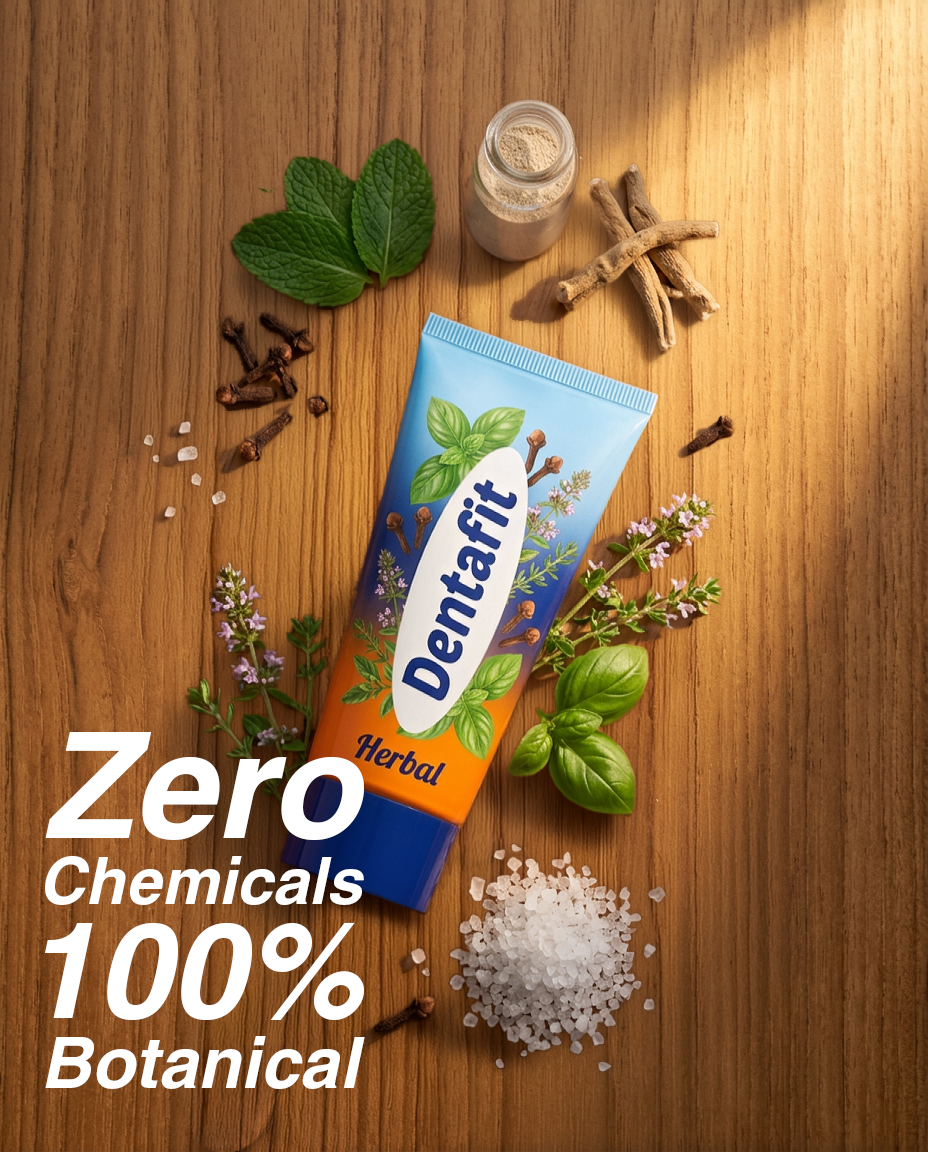 Tubed DentaFit Herbal toothpaste laid diagonally on a wooden surface, surrounded by mint, herbs, salt crystals and spices, conveying 'Zero Chemicals, 100% Botanical'.